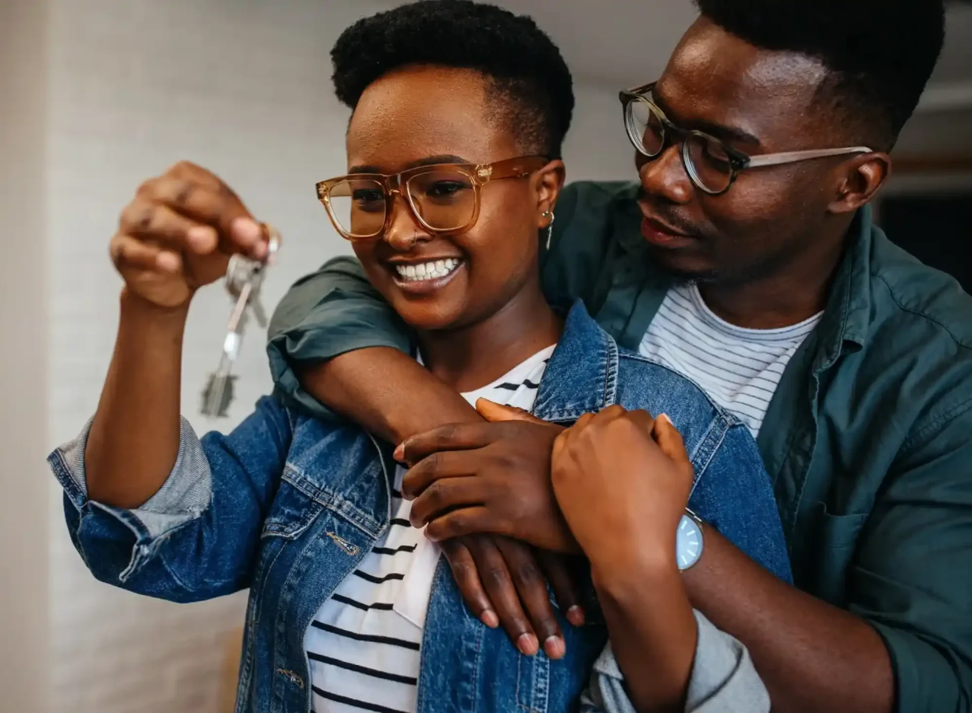 A man and woman holding keys to their new home.