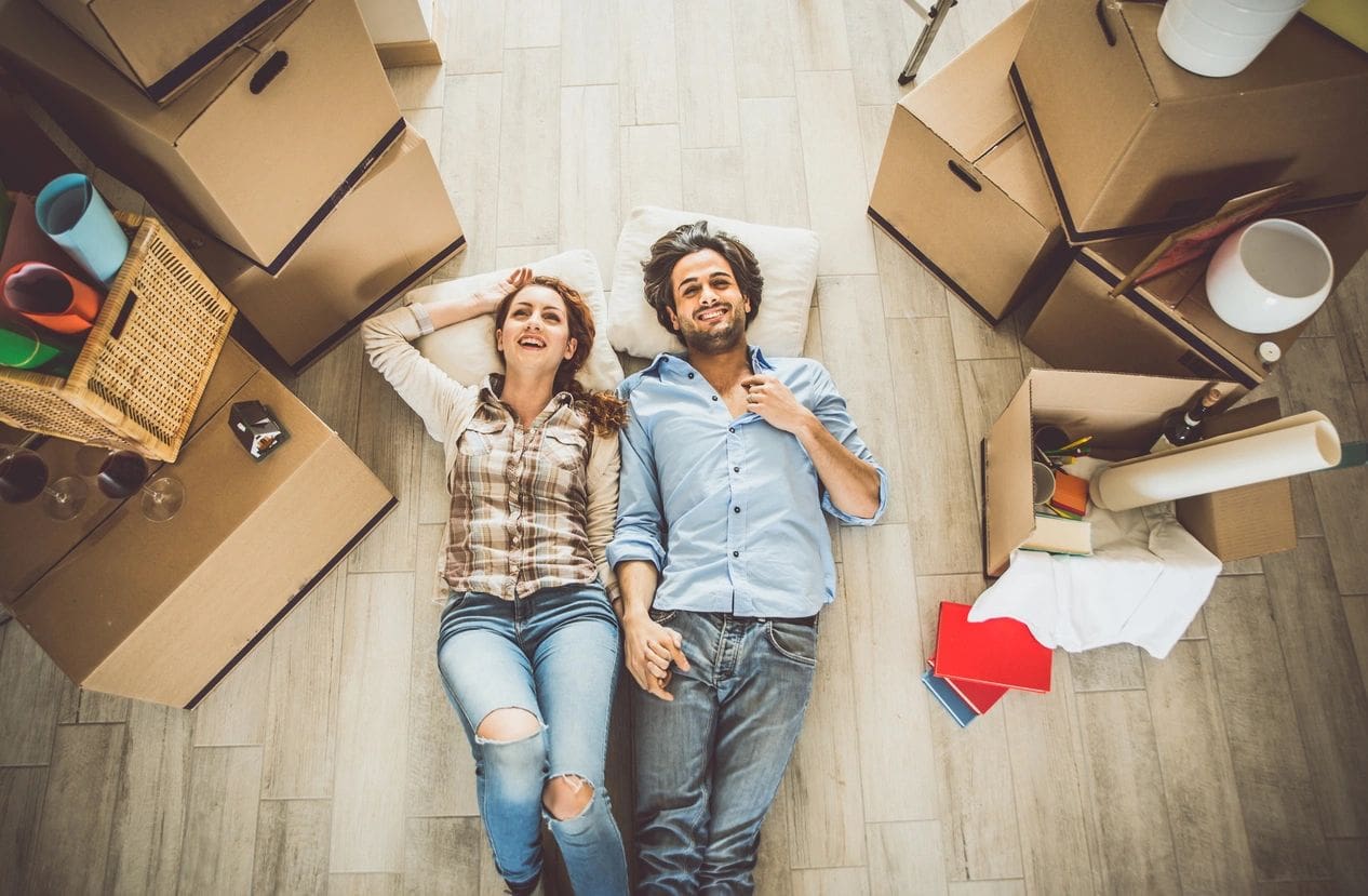 A man and woman laying on the ground with boxes.