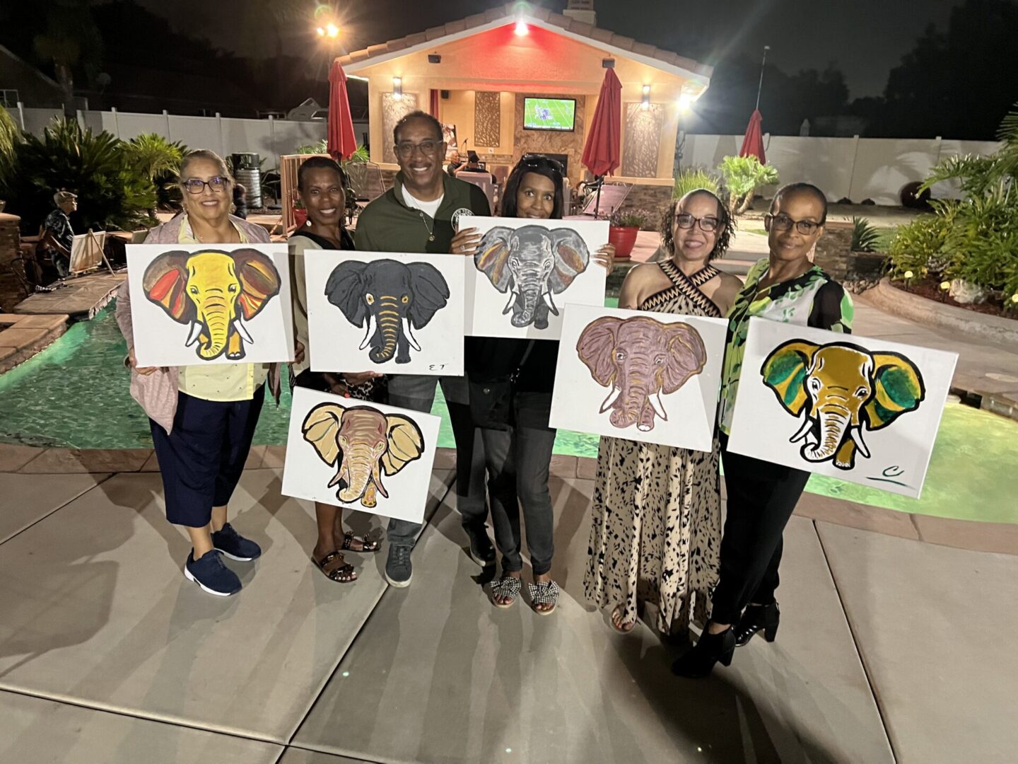 A group of people holding up paintings of elephants.